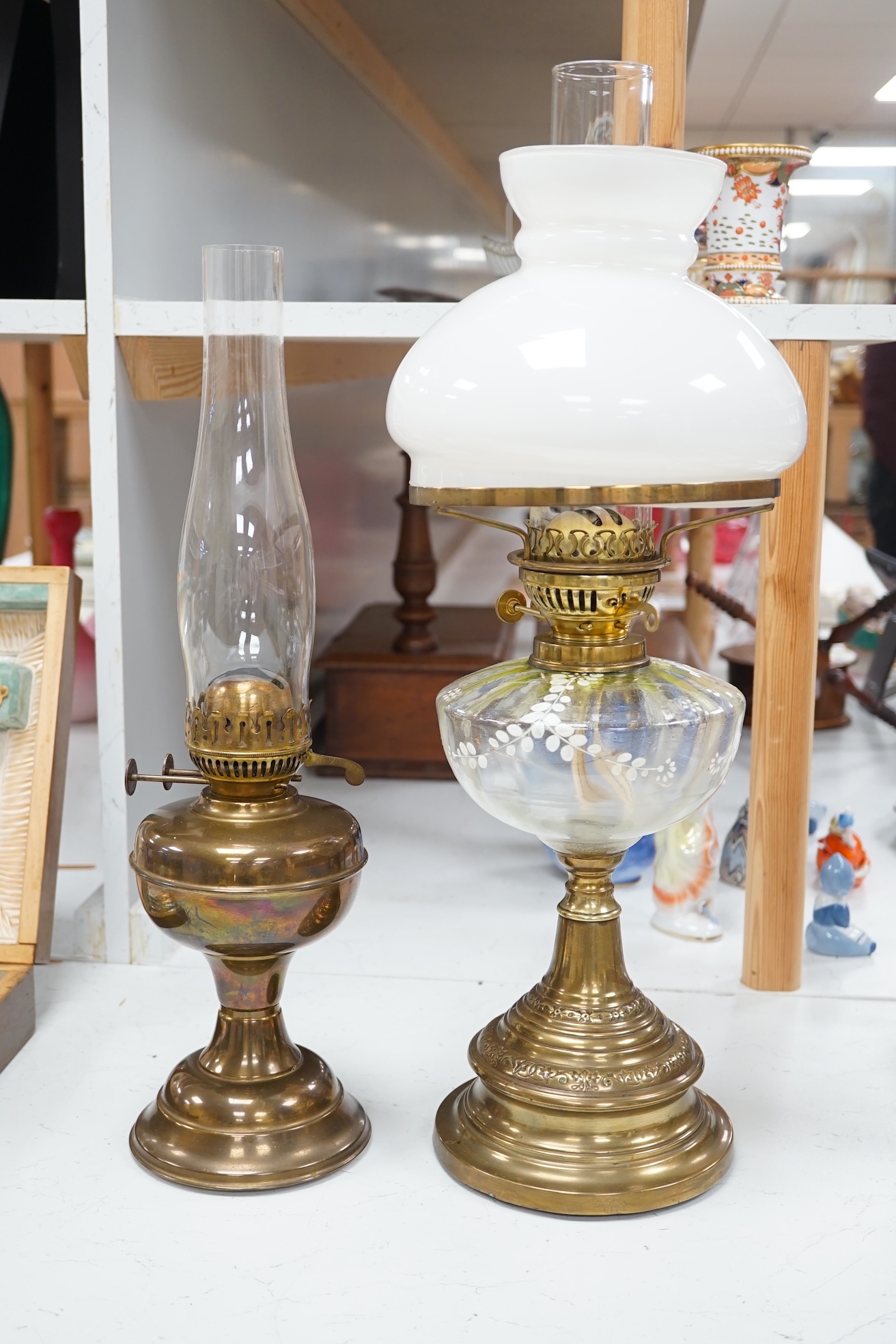 A late 19th century brass oil lamp with painted bowl and opaque shade together with a later oil lamp, largest 59cm high. Condition - fair to good